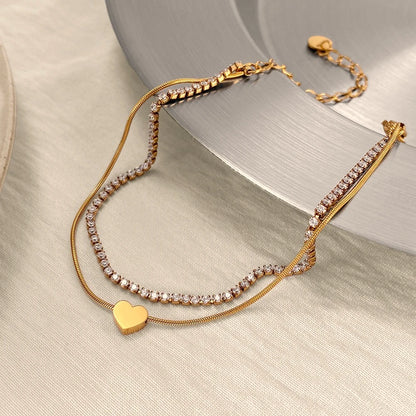 The Duo Gold Heart Charm Double Layer Bracelet — styled flat lay on marble tray with dried flowers showing full bracelet and lobster clasp detail