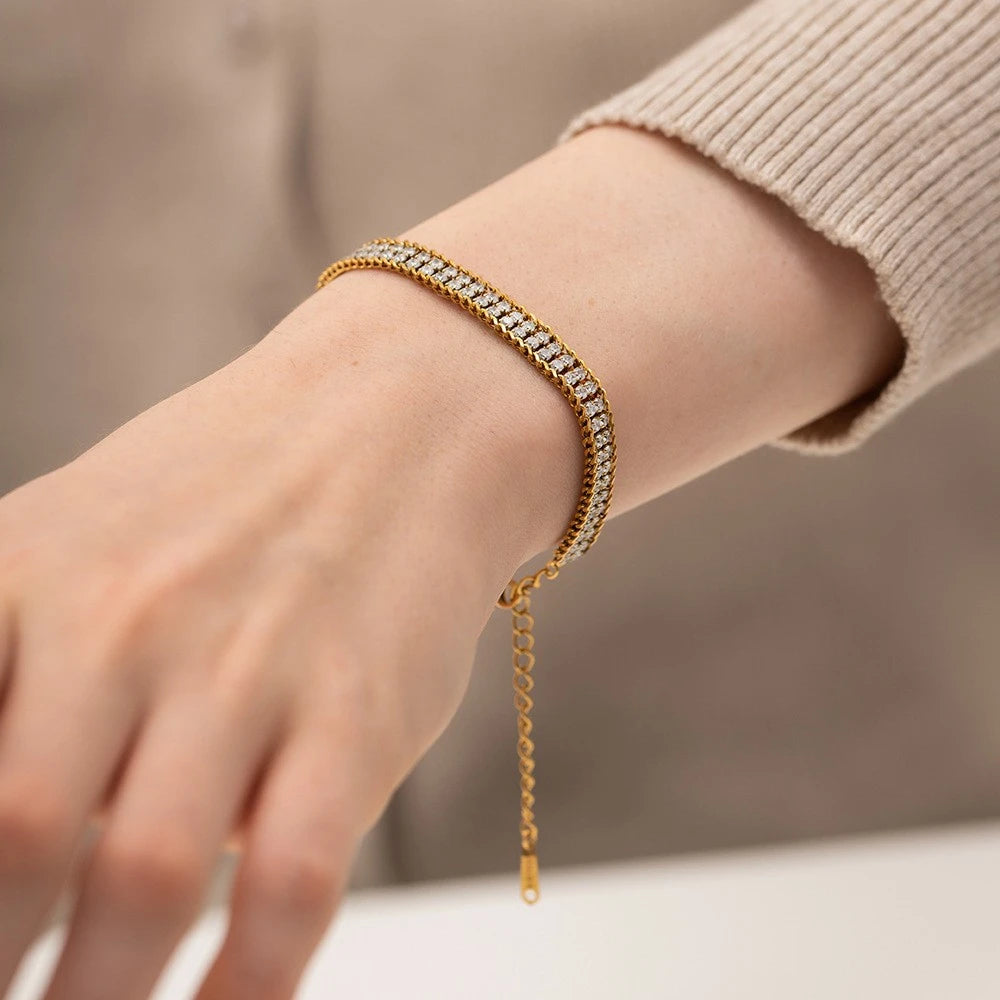The Armour Gold Crystal-Framed Wide Band Bracelet — flat lay on cream silk showing full bracelet with lobster clasp end and rectangular gold tag on extender