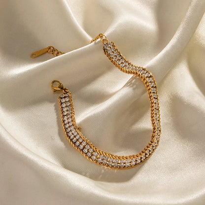 The Armour Gold Crystal-Framed Wide Band Bracelet — styled on white marble tray with dried flowers showing full band and lobster clasp with extender chain