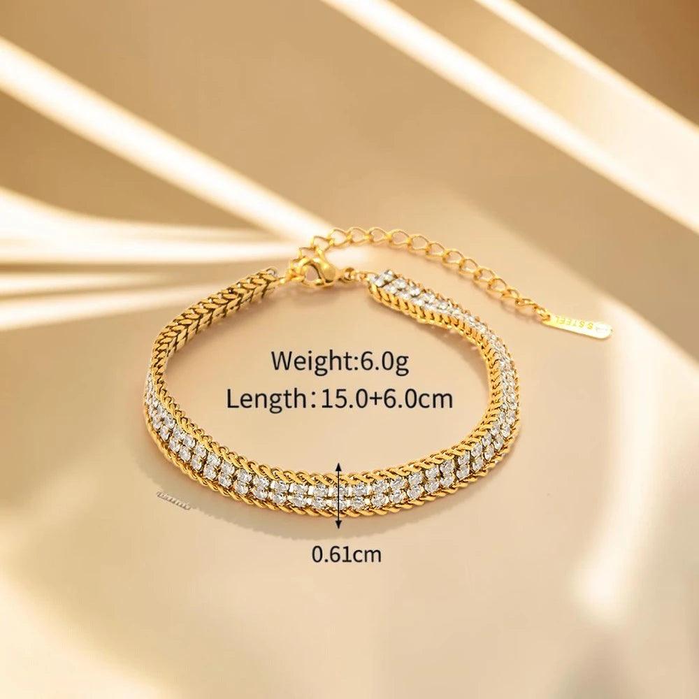 The Armour Gold Crystal-Framed Wide Band Bracelet — draped on cream silk fabric showing double-row crystal paving with gold wheat chain edges detail