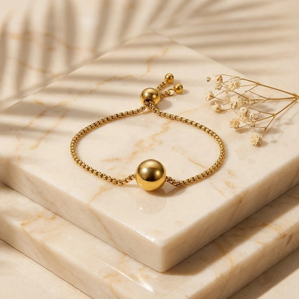 The Orbit Gold Sphere Slider Bracelet — worn on wrist showing polished gold sphere centrepiece on fine box chain with sliding ball closure tail visible below