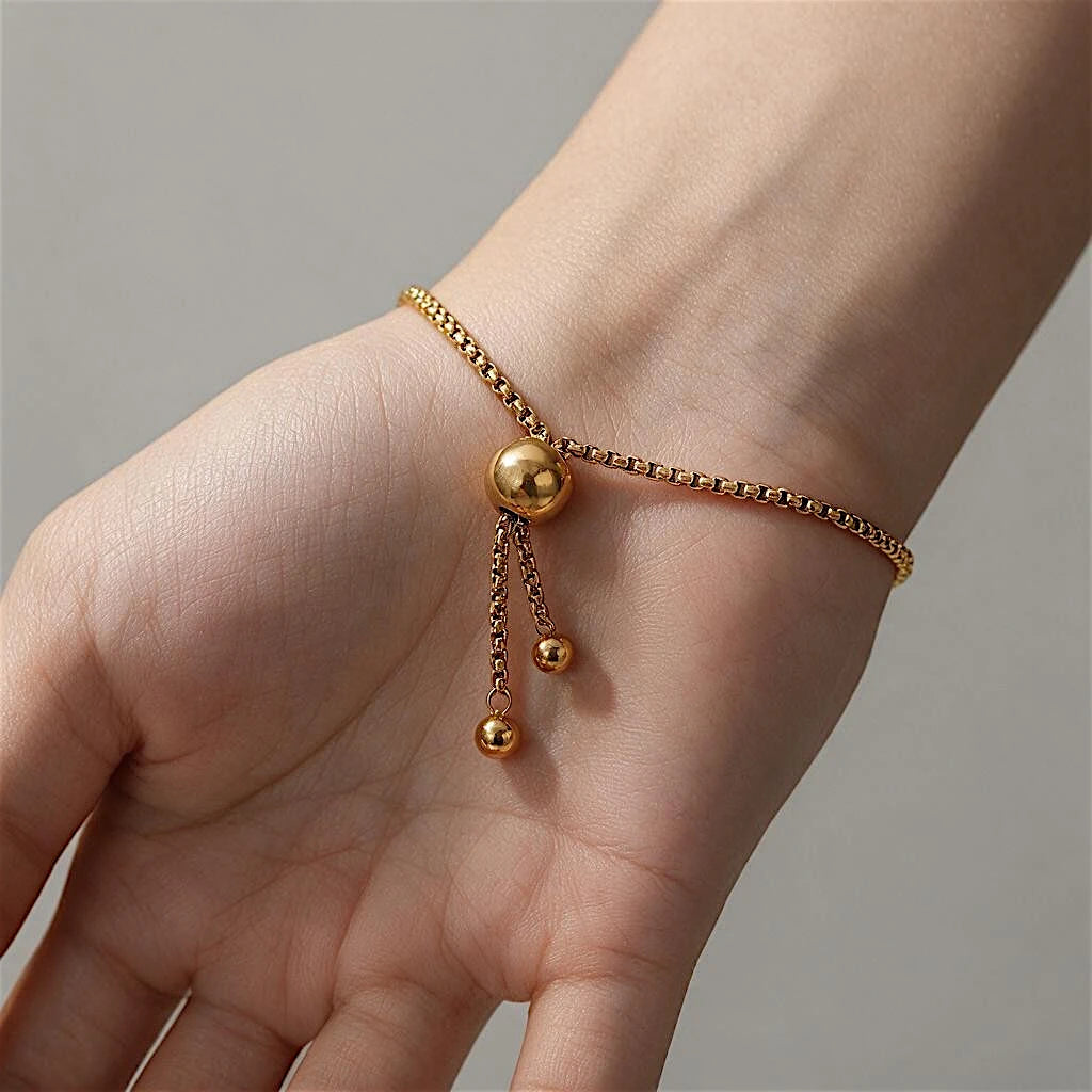 The Orbit Gold Sphere Slider Bracelet — flat lay on cream ceramic plate showing full bracelet circle with sphere at centre and sliding closure at opposite side